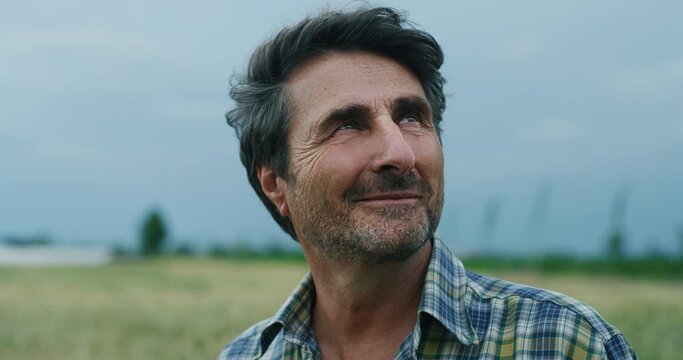 Cinematic shot of a mature male farmer satisfied with his work is enjoying a nature around him on a countryside farm fields.