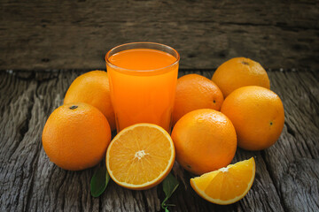 Fresh orange fruits with leaves on wooden table. Glass of Fresh Orange Juice.