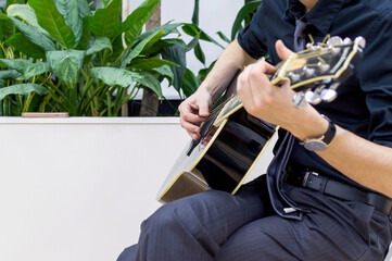Man in black plays the acoustic guitar