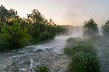 Rough river with fast-flowing in the fog and mist on the background