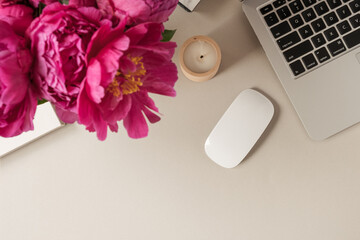 Laptop, beautiful pink peony tulip flowers bouquet on beige table background. Flat lay, top view minimalist home office desk workspace.