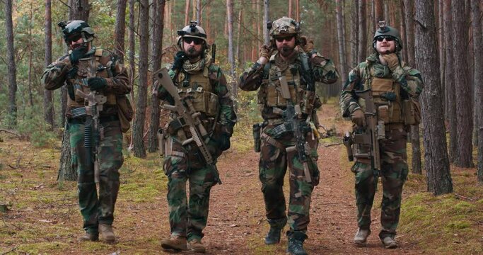 Fully equipped soldiers in camouflage uniform returning from reconnaissance in a pine forest