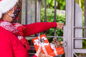 Coronavirus and Christmas 2020. Senior woman wearing Santa hat and face mask for coronavirus ring...