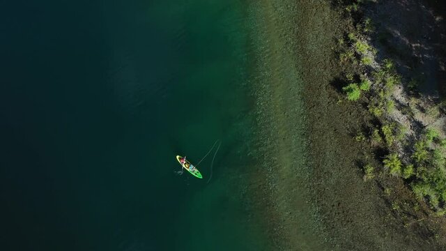 Aerial top down of two trained fishers catching trouts with dry fly technique near the shore in Lake Steffen, Patagonia Argentina.