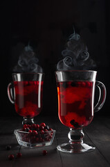 Christmas red hot mulled wine with berries and steam as Christmas tree shape in two transparent...