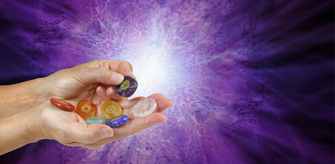 Offering third eye chakra healing stone - female holding red, orange, yellow, green, blue, indigo...