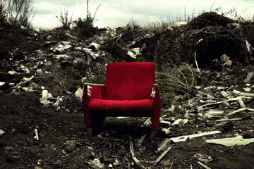 The old chair is in a landfill. Abandoned wasteland with waste and garbage.