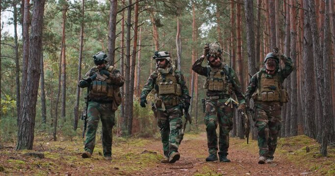 Fully equipped soldiers in camouflage uniform returning from reconnaissance in a pine forest