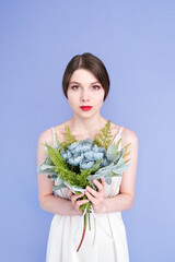 Girl with a bouquet isolated on a purple background. Girl with red lips holds a bouquet of flowers.