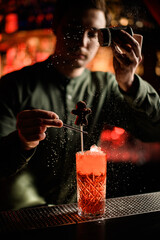 bartender accurate decorates glass with cocktail with chocolate candy and sprinkles with powdered sugar