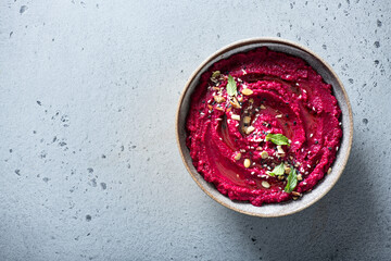 beet hummus in a ceramic bowl on a light background, top view, copy space - obrazy, fototapety, plakaty