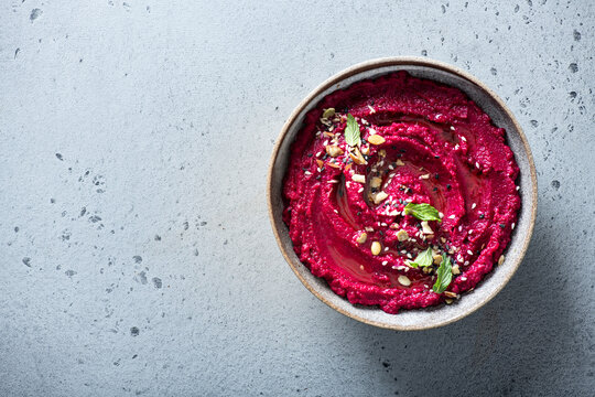 beet hummus in a ceramic bowl on a light background, top view, copy space