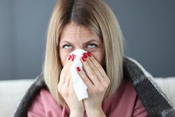 Sick woman blows her nose into handkerchief.