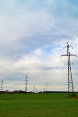 Landscape with high-voltage power lines. Electricity distribution station. Pylons in field