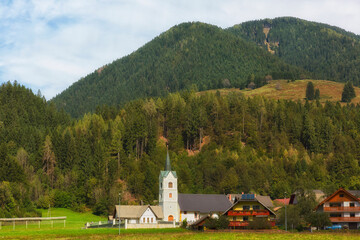 A small village with a church on a background of mountains, Alps