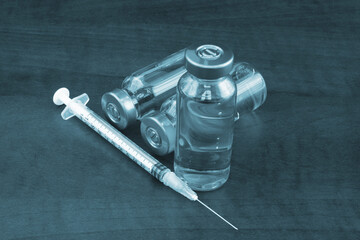 Vaccine bottles and syringe on wooden background. Vaccination concept.