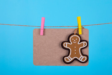 Gingerbread man on cardboard with laundry clips against light blue background