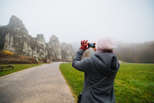 Girl taking pictures on the phone. Externsteine rock formation, German Stonehenge.