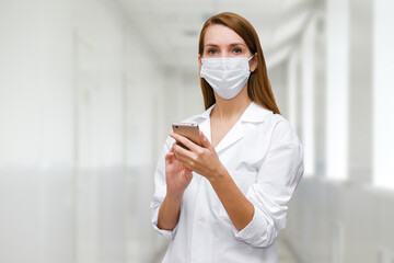 Doctor in a medical mask and white robe stands in the hall of the hospital. Doctor treating for a coronavirus infection.