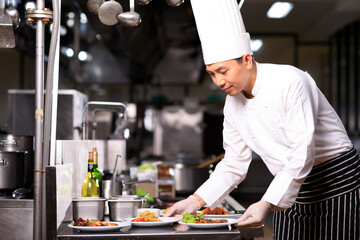 Asian Male chef presenting the dish in the kitchen. Selective focus.