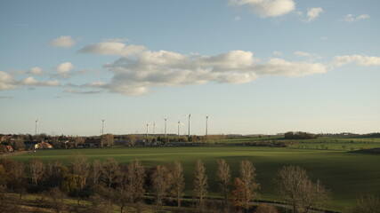 Feld in Langzeitbelichtung zur Golden Hour mit kleinem Dorf und Windr&auml;dern