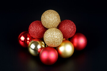 Pyramid from a red and gold shiny and matte christmas balls close up view on black background