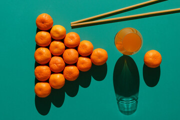 Tangerines are laid out on a billiard table in the form of a classic pyramid of 16 balls with long pasta imitating billiard cues and a glass of tangerine juice