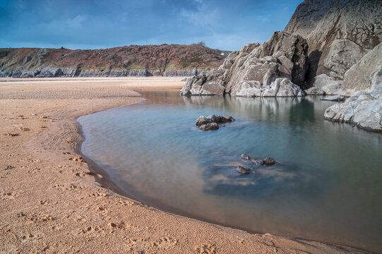Tidal rock pools on a beach in south Wales. The day is sunny