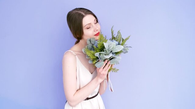 Girl with a bouquet isolated on a purple background.  Girl with red lips holds a bouquet of flowers.
