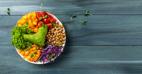 Buddha bowl vegetarian, vegan dish with avocado, tomato, red cabbage, chickpea, fresh lettuce salad, pumpkin, persimmon. banner, catering menu recipe place for text, top view