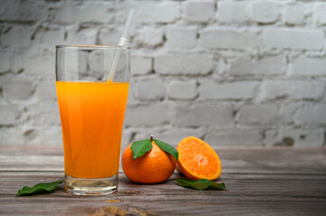 Fresh orange juice on wooden table over white brick background