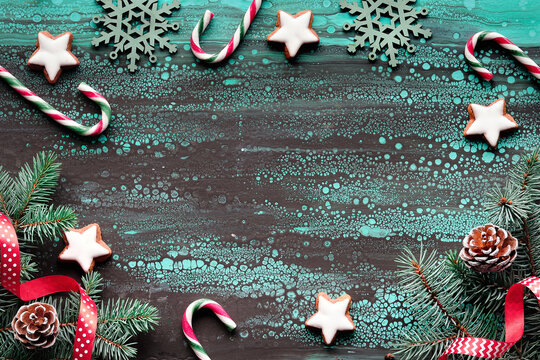 Zero waste Christmas background decorated with natural Xmas tree. Fir twigs, stripy candy canes, pine cones, ribbons, star cookies. Frame with copy-space on turquoise acrylic liquid art background.
