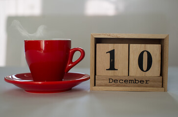 Cube wooden calendar showing date on 10th December with red cup of hot coffee over white background. Advent calendar, Christmas background, Copy space