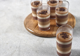 Triple layered pudding made from chocolate, vanilla and coffe in glass.