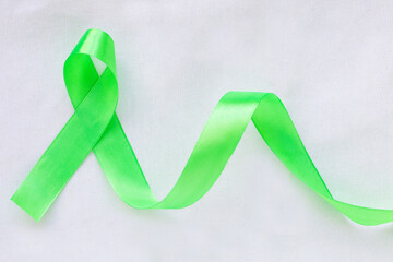 Obraz na płótnie Canvas Emerald green or jade green ribbon curl on white fabric background with copy space, symbol for Liver Cancer awareness, World Cancer Day. Healthcare or hospital and insurance concept.