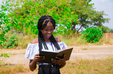 a young beautiful african school student feeling excited as she is going through her notebook.