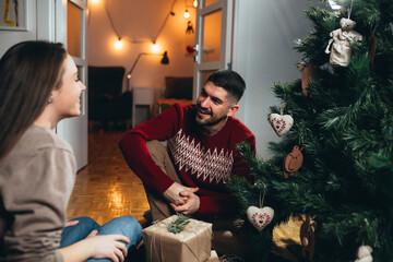 happy couple decorating christmas tree at home