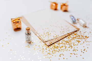 Blank note with envelope, gifts and gold glitter stars on white background