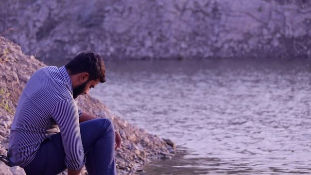 Young Boy Throwing Stones in a River,relax indian boy and Throwing Stones in water Lake,indian people free timepass