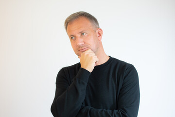 Young man in casual black sweater thinking over white background.