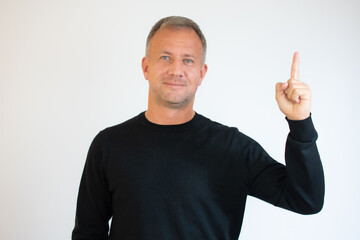 Portrait of a man pointing finger up at copy space isolated over white background