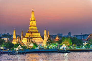 Naklejka premium Night Illuminated Temple of Dawn or Wat Arun and Thonburi west bank of Chao Phraya River at sunset. Bangkok, Thailand