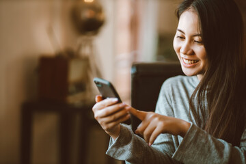 Closeup portrait young Asian beautiful woman smiling and using a smartphone for business or...
