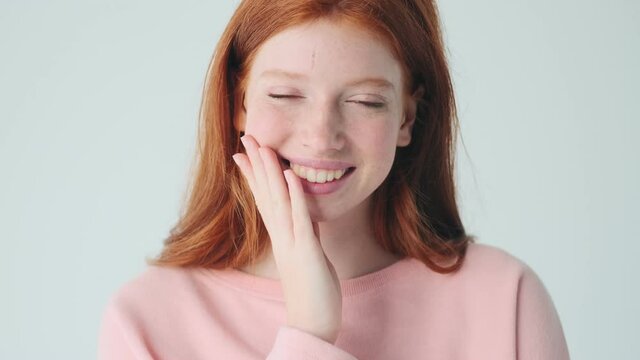 Laughing cute redhead girl posing isolated over white wall background