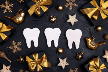 White teeth with gold decorations and gift boxes on black background. Dentist Merry Christmas and New Year concept.