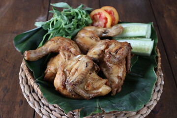 Ayam Goreng berempah. Chicken fried with spices, lemon grass and ginger, famous food in Malaysia and Indonesia. served with cucumber, tomato and basil.