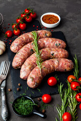 raw sausages with ingredients on a cutting board on a stone background - 396757188