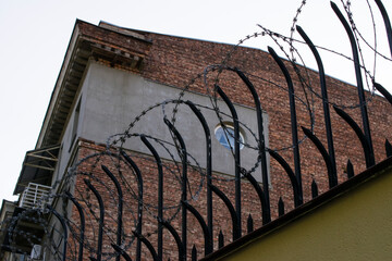 Stone fence with metal rods and barbed wire on top.Prison wall, boundary, symbol of jail