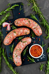 Grilled sausages with rosemary herbs on a black background. Top view - 396757384