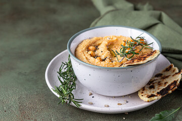 Classic hummus with rosemary, flatbread, boiled chickpea and olive oil, green stone background. Traditional Middle Eastern snack.